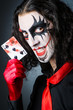Evil clown with cards in dark room
