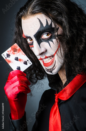 Photo: Evil clown with cards in dark room Evil clown with cards in dark room