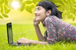 Happy girl lying on grass with laptop
