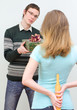 Woman hiding rolling pin underhand talking to man