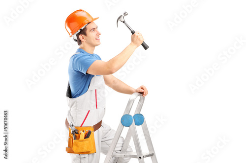 Photo: A repairman on a ladder working with a hammer A repairman on a ladder working with a hammer