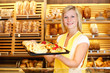 Shopkeeper in baker shop with tablet full of cake