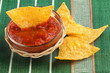 bowl of hot sauce with nachos on green tablecloth