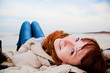 Foto: Smiling happy woman lying on the beach on a spring or autumn day Smiling happy woman lying on the beach on a spring or autumn day