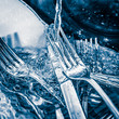 Blue toned image of forks and knives  washed on a sink