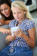 Teenager using smartphone with adult beside her