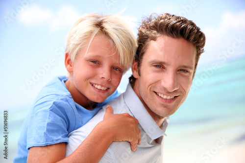 Photo: Daddy giving piggyback ride to son by the beach Daddy giving piggyback ride to son by the beach