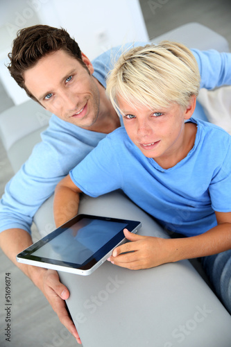 Photo: Father and son using digital tablet at home Father and son using digital tablet at home