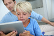 Father and son using digital tablet at home
