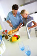 Man with young girl preparing meal in kitchen