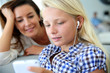 Teenager using smartphone with adult beside her