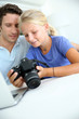 Father and daughter looking at digital camera and laptop
