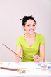 Beautiful young woman painter at work, on color background
