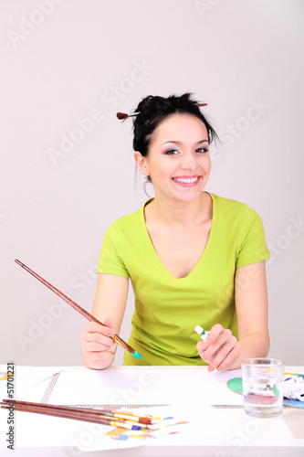 Photo: Beautiful young woman painter at work, on color background Beautiful young woman painter at work, on color background