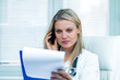 Photo: Pretty Young Female Doctor Is Consulting Results by Cellphone Pretty Young Female Doctor Is Consulting Results by Cellphone