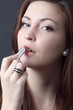 Foto: beautiful young woman applying lipstick beautiful young woman applying lipstick