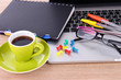 Laptop with stationery and cup of coffee on table