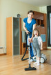Woman teaches  girl to use the vacuum cleaner