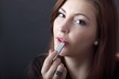 Foto: beautiful young woman applying lipstick beautiful young woman applying lipstick