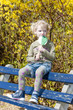 Photo: little girl with a lollipop sitting on bench in spring little girl with a lollipop sitting on bench in spring