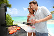 Cheerful couple in holidays preparing grilled meat