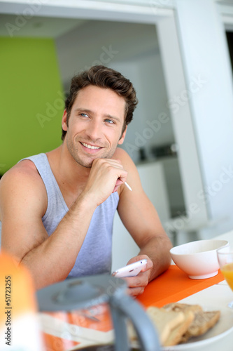 Photo: Man using smartphone while having breakfast Man using smartphone while having breakfast