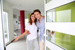 Cheerful couple inviting people to enter in home
