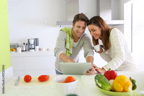 Photo: Couple in home kitchen looking for lunch recipe Couple in home kitchen looking for lunch recipe
