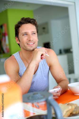 Photo: Man using smartphone while having breakfast Man using smartphone while having breakfast