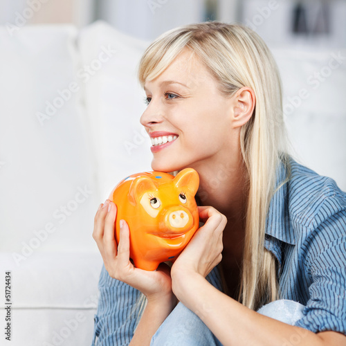 Photo: attraktive frau hält sparschwein in der hand attraktive frau hält sparschwein in der hand