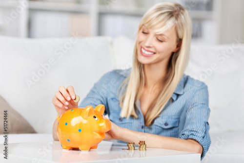 Photo: frau wirft geld ins sparschwein frau wirft geld ins sparschwein