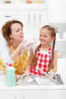 Woman and little girl having fun washing the dishes