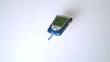 Blood glucose monitor falling on white surface