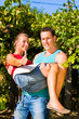 Man carries woman on his arms in vineyard