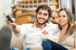 Young couple watching tv on a sofa