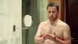 Vídeo: Young man applying face cream in front of mirror Young man applying face cream in front of mirror