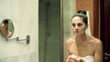 Vídeo: Young woman washing off face mask in front of mirror Young woman washing off face mask in front of mirror