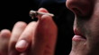 Man smoking a joint, close up on black