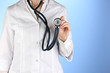 Photo: Doctor with stethoscope in hands on blue background Doctor with stethoscope in hands on blue background