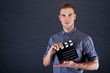 Man with movie clap over dark background