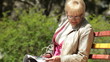Senior Woman Reading Magazine In The Park