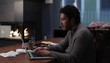 Hispanic man at home at table with laptop typing