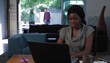Black woman at home working on laptop as she is greeted by husband