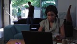 Video: Black woman using credit card at home working on laptop with partner in background on phone Black woman using credit card at home working on laptop with partner in background on phone