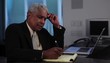 Senior businessman using laptop and making notes