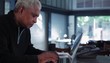 Senior man at home typing on laptop