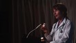 Doctor at lectern speaking while holding prescription bottles