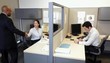 Businessman shaking hands with businesswoman in office cubicle