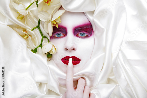 Photo: Hübsche junge Frau mit tollem Make Up hält Finger an Mund Hübsche junge Frau mit tollem Make Up hält Finger an Mund