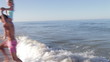 Father Carrying Daughter On Shoulders As They Run In Sea